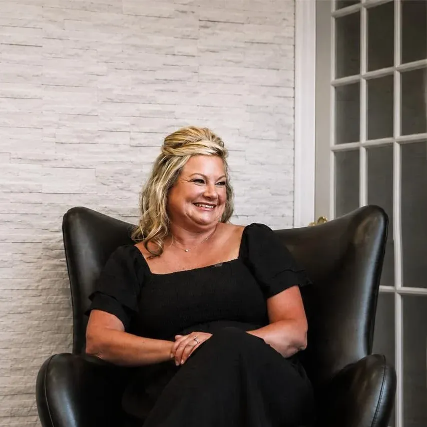 Christa Tippit seated in a leather armchair beside a stone accent wall